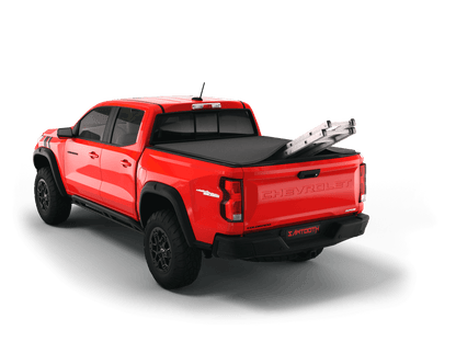 Red Chevrolet Colorado / GMC Canyon with ladder sticking out of Sawtooth Stretch expandable truck bed cover