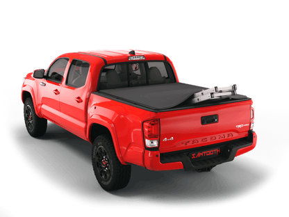 Red Toyota Tacoma with ladder sticking out of Sawtooth Stretch expandable truck bed cover