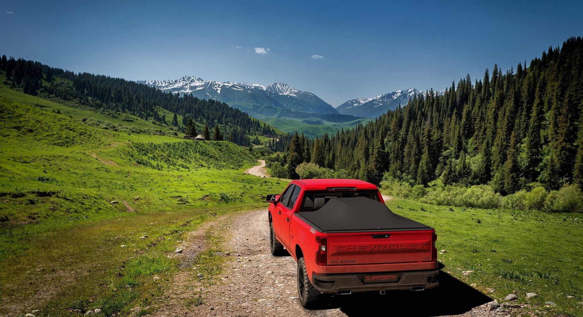 Red Chevrolet Silverado 2500HD / 3500 HD / GMC Sierra 2500HD / 3500HD with large cargo under a Sawtooth Stretch expanded tonneau in the mountains