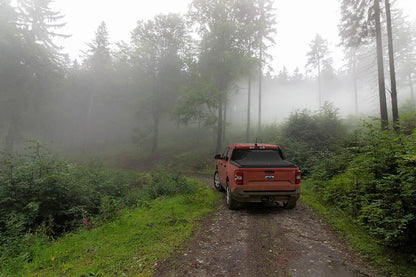 Red 2023 Ford Maverick with Sawtooth Stretch tonneau expanded over tall cargo load in misty mountains